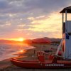 Una torretta di salvataggio su una spiaggia al tramonto, con un gommone rosso.