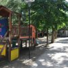 Parco giochi con scivoli e panchine ombreggiate.