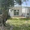Bungalow bianco con veranda, vicino a un albero.