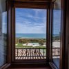Vista mare da una finestra, piscine e giardino in basso.