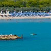 Spiaggia affollata con mare calmo e kayak.