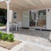 Veranda pavimentata con tavolo e sedie bianche.