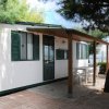 Casa mobile bianca con veranda, tavolo e sedie.