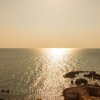 Tramonto su mare e scogli illuminati dal sole.