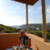 Persona seduta a un tavolo apparecchiato su una terrazza con vista mare.