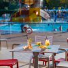 Tavolo con bevande e snack vicino a una piscina affollata.