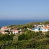 Vista di un complesso di villette vicino al mare con piscina, circondato da vegetazione.