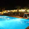 Piscina illuminata di notte, circondata da palme e scivoli colorati.