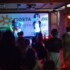 Persone assistono a spettacolo con animatori su palco.