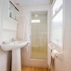 Un bagno con lavabo, specchio, doccia e pavimento in legno chiaro.