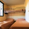Camera con due letti singoli e un letto a castello, copriletti marroni.