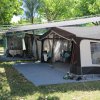 Tenda da campeggio montata su erba con ombra degli alberi.