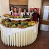 Sei persone posano dietro un tavolo ricco di frutta decorata.