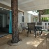 Un'ampia veranda in legno con tavolo e sedie, circondata da alberi.