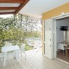 Veranda con tavolo e sedie bianche all'aperto, vista su giardino e ingresso alla stanza.