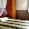 Camera da letto con letto matrimoniale, zanzariera, armadio in legno e tendaggi chiari.
