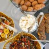 Vassoi di frutta secca, banane, noci e biscotti assortiti su un tavolo.