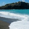 Bambino gioca sulla spiaggia di ciottoli con onde che si infrangono.