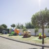 Area giochi per bambini con strutture colorate e alberi lungo la strada.