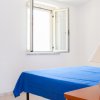 Camera semplice con letto blu, finestra aperta e lampada su un comodino.