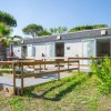 Edificio con piccole unità abitative, rampe di legno, palmizi e fiori.