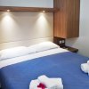 Letto con copriletto blu, asciugamani arrotolati, fiori rossi.