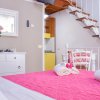 Letto con copriletto rosa, scale in legno, vaso di fiori.