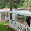 Verande bianche di bungalow in giardino verde con alberi.