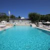 Piscina grande con ombrelloni e sedie a sdraio sotto un cielo blu.