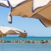 Due ombrelloni in primo piano con mare e bagnanti sullo sfondo.