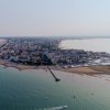 Vista aerea di una città costiera con spiaggia e porto.