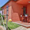 Entrata di una casa arancione con veranda, mobili da esterno e palla colorata sul prato.