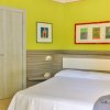 Camera da letto con parete verde, letto matrimoniale e quadri colorati.
