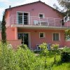 Casa rosa a due piani con balcone e giardino.