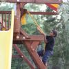 Bambino arrampica su una struttura da gioco in legno con una corda.