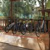 Un portabiciclette in legno con sei biciclette parcheggiate all'aperto.