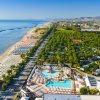 Vista aerea di una spiaggia e piscina con ombrelloni.