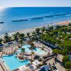 Piscina e spiaggia con mare cristallino dall'alto.