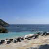 Lettini a bordo piscina con vista sul mare e colline verdi.