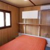 Letto matrimoniale arancione in una camera con pareti di legno, finestra e condizionatore.