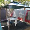 Gazebo con tavolo e sedie davanti a una tenda, immerso nel verde.