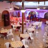 Sala ristorante con tavoli apparecchiati e sedie bianche.