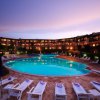Piscina illuminata al tramonto con sdraio attorno.
