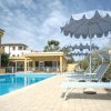 Una piscina con lettini e ombrelloni blu sotto un cielo nuvoloso.