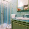 Bagno con doccia a vetri e piastrelle verdi.