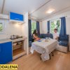 Interno di una casa mobile con angolo cottura blu e due persone sedute a un tavolo.