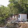 Case mobili bianche tra gli alberi con una staccionata di legno.