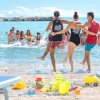 Persone giocano e si divertono in mare, con giochi sulla spiaggia.