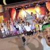 Bambini e adulti festeggiano davanti a un palco.