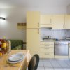 Cucina moderna con mobili gialli, tavolo apparecchiato e divano con cuscini colorati.